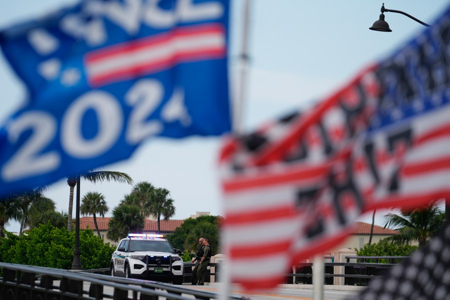 Police patrol on a bridge beside the Mar-a-Lago estate of Republican presidential nominee and former President Donald Trump, as a supporter flies flags to express support for Trump one day after an apparent assassination attempt, in Palm Beach, Fla., Monday, Sept. 16, 2024. (AP Photo/Rebecca Blackwell)