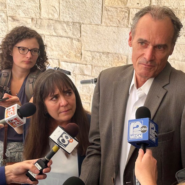 Former University of Wisconsin-La Crosse Chancellor Joe Gow, right, and his wife, Carmen Wilson, center, take questions after a hearing before a committee that will determine whether he can teach after being fired as the campus leader for making pornographic videos, Friday, Sept. 20, 2024, in Madison, Wis. (AP Photo/Scott Bauer)