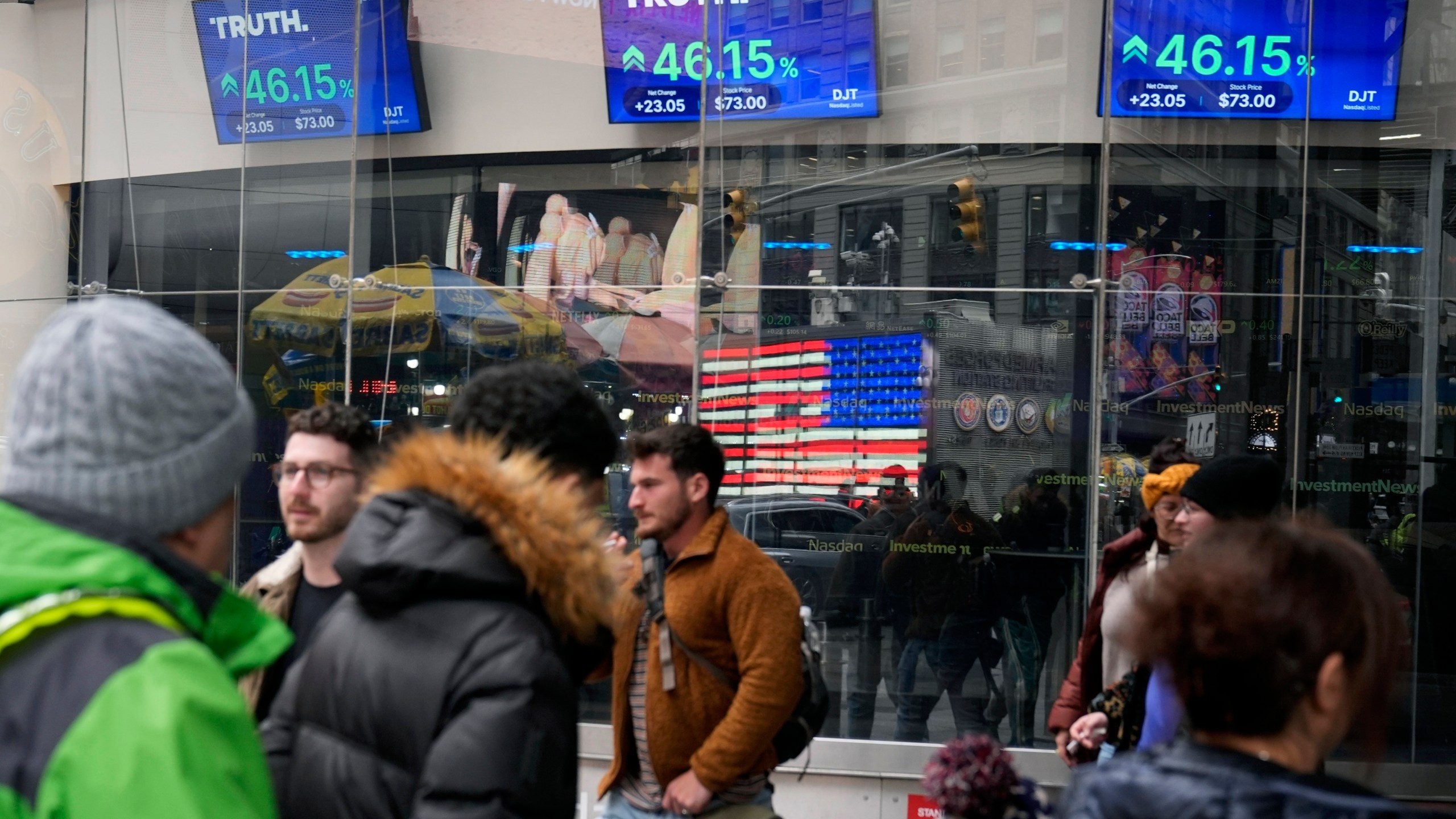 FILE - Pedestrians walk past the Nasdaq building as the stock price of Trump Media & Technology Group Corp. is displayed on screens, March 26, 2024, in New York. (AP Photo/Frank Franklin II, File)