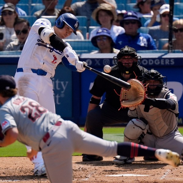 Los Angeles Dodgers' Shohei Ohtani, second from left, hits a solo home run as Cleveland Guardians starting pitcher Tanner Bibee, left, watches along with catcher Bo Naylor, right, and home plate umpire Dan Bellino during the fifth inning of a baseball game, Sunday, Sept. 8, 2024, in Los Angeles. (AP Photo/Mark J. Terrill)