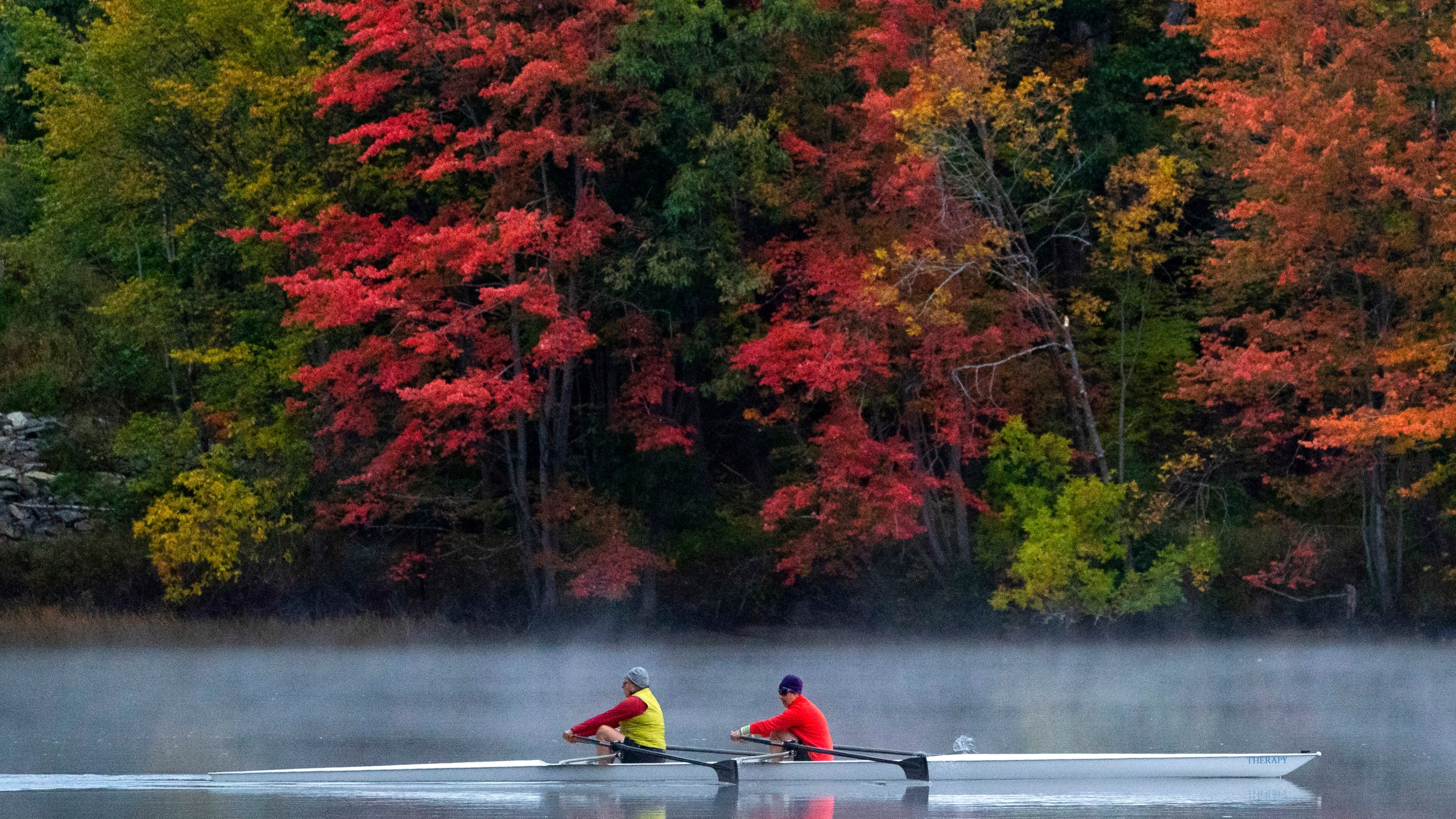 FILE - A pair of rowers glide on the Androscoggin River in Brunswick, Maine, where the foliage has changed to autumn colors, Oct. 10, 2021. (AP Photo/Robert F. Bukaty, File)