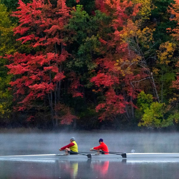 FILE - A pair of rowers glide on the Androscoggin River in Brunswick, Maine, where the foliage has changed to autumn colors, Oct. 10, 2021. (AP Photo/Robert F. Bukaty, File)