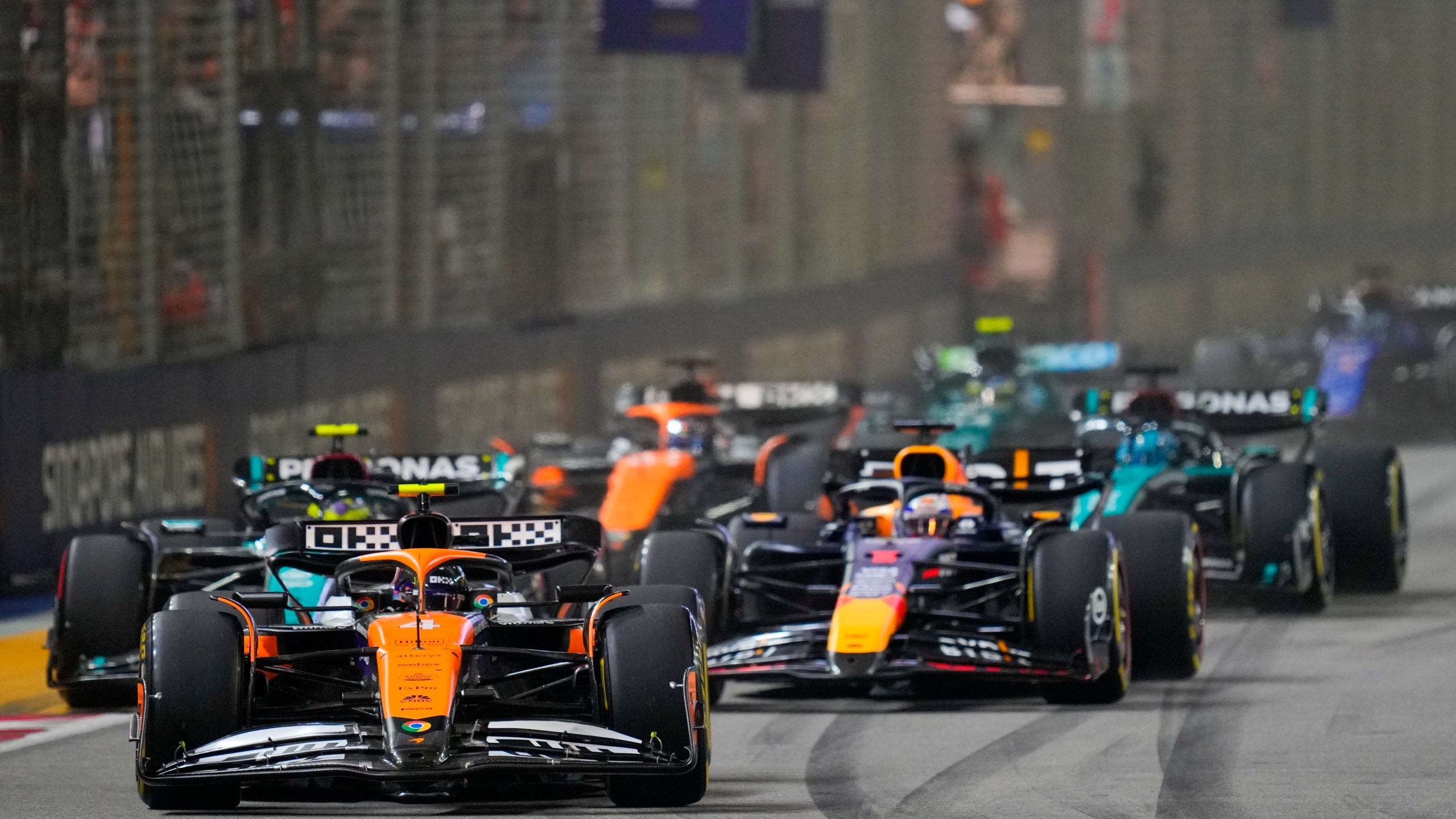 McLaren driver Lando Norris, left, of Britain leads Red Bull driver Max Verstappen of the Netherlands into turn one at the start of the Singapore Formula One Grand Prix at the Marina Bay Street Circuit, in Singapore, Sunday, Sept. 22, 2024. (AP Photo/Vincent Thian)