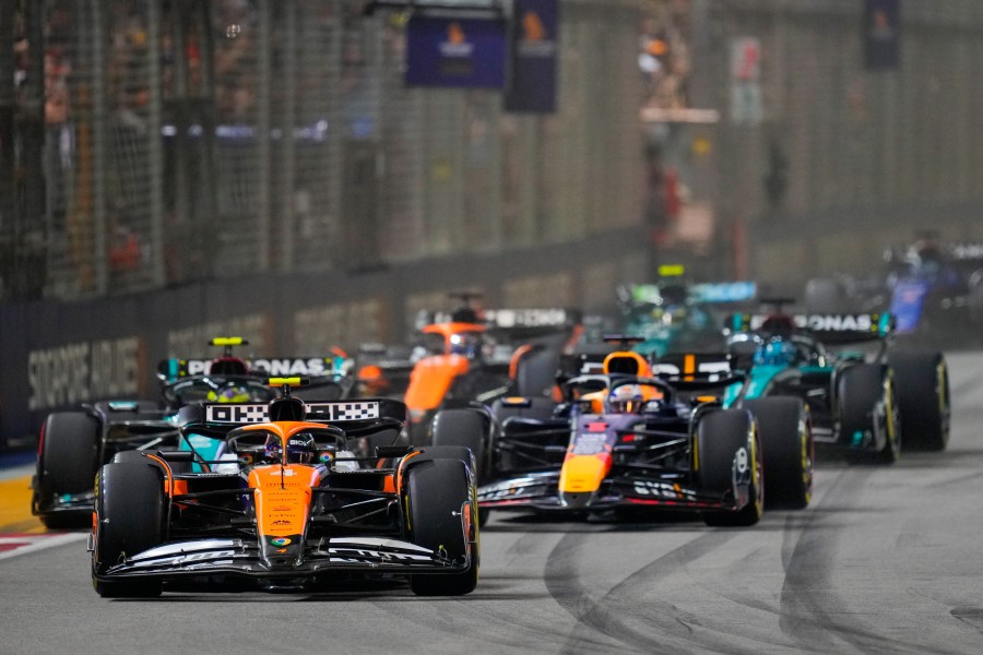 McLaren driver Lando Norris, left, of Britain leads Red Bull driver Max Verstappen of the Netherlands into turn one at the start of the Singapore Formula One Grand Prix at the Marina Bay Street Circuit, in Singapore, Sunday, Sept. 22, 2024. (AP Photo/Vincent Thian)