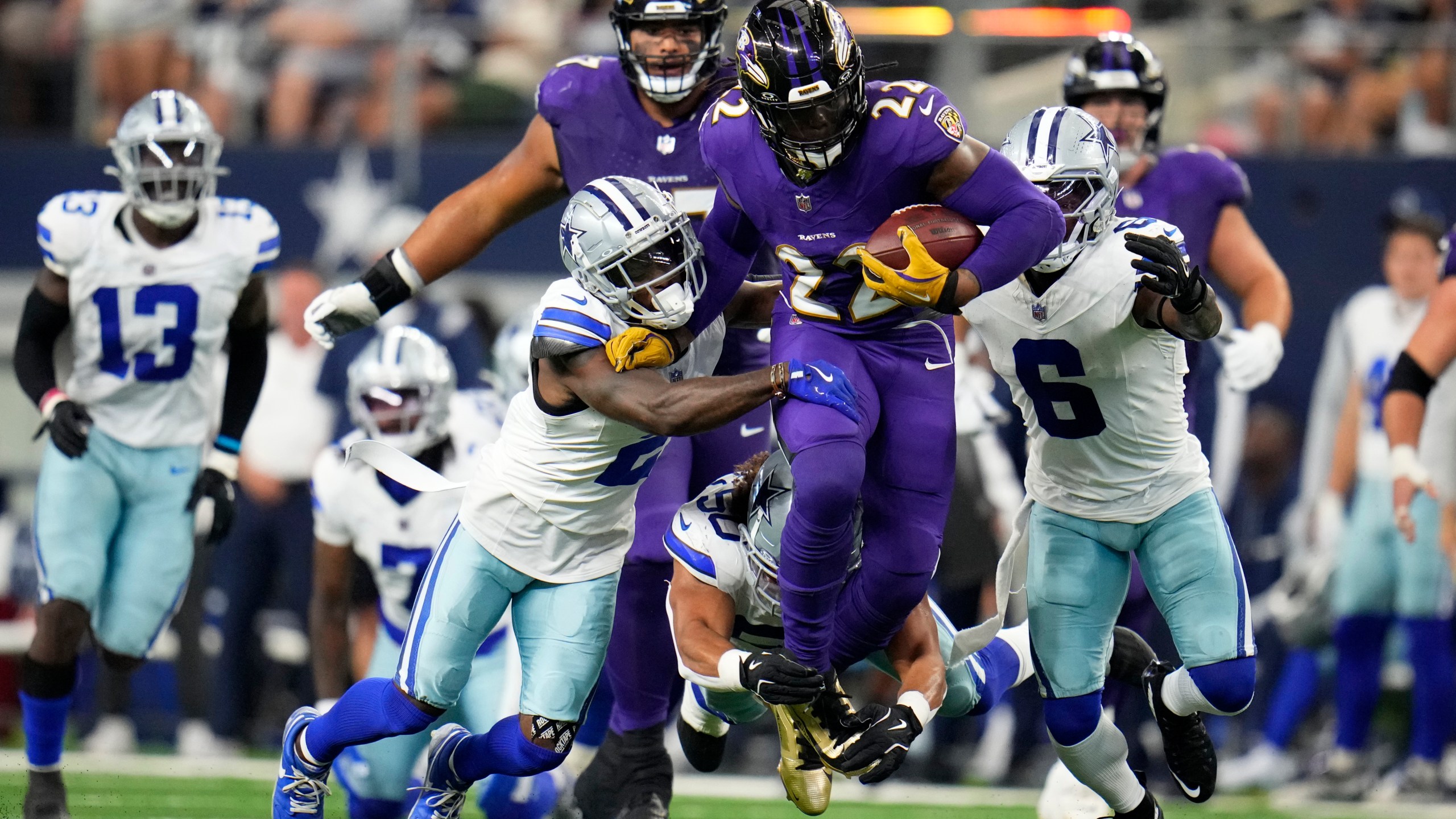 Baltimore Ravens running back Derrick Henry (22) runs the ball as Dallas Cowboys' Jourdan Lewis (2), Eric Kendricks, bottom, and Donovan Wilson (6) attempt to make the stop in the first half of an NFL football game in Arlington, Texas, Sunday, Sept. 22, 2024. (AP Photo/Julio Cortez)