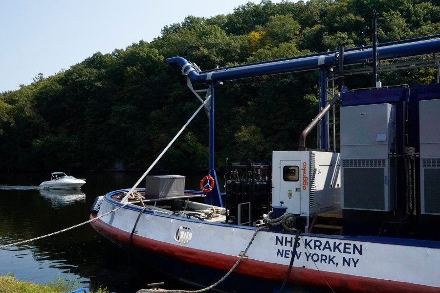 A boat, left, passes by the NH3 Kraken, a tugboat powered by ammonia, Friday, Sept. 13, 2024, in Kingston, N.Y. (AP Photo/Alyssa Goodman)