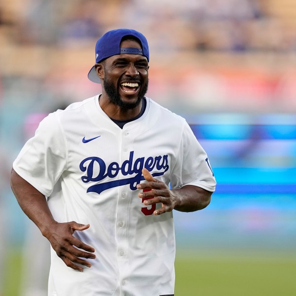 FILE - Former NFL and University of Southern California running back Reggie Bush, left, jokes with laughs after throwing out the ceremonial first pitch prior to a baseball game between the Los Angeles Dodgers and the Cincinnati Reds Friday, May 17, 2024, in Los Angeles. (AP Photo/Mark J. Terrill, File)