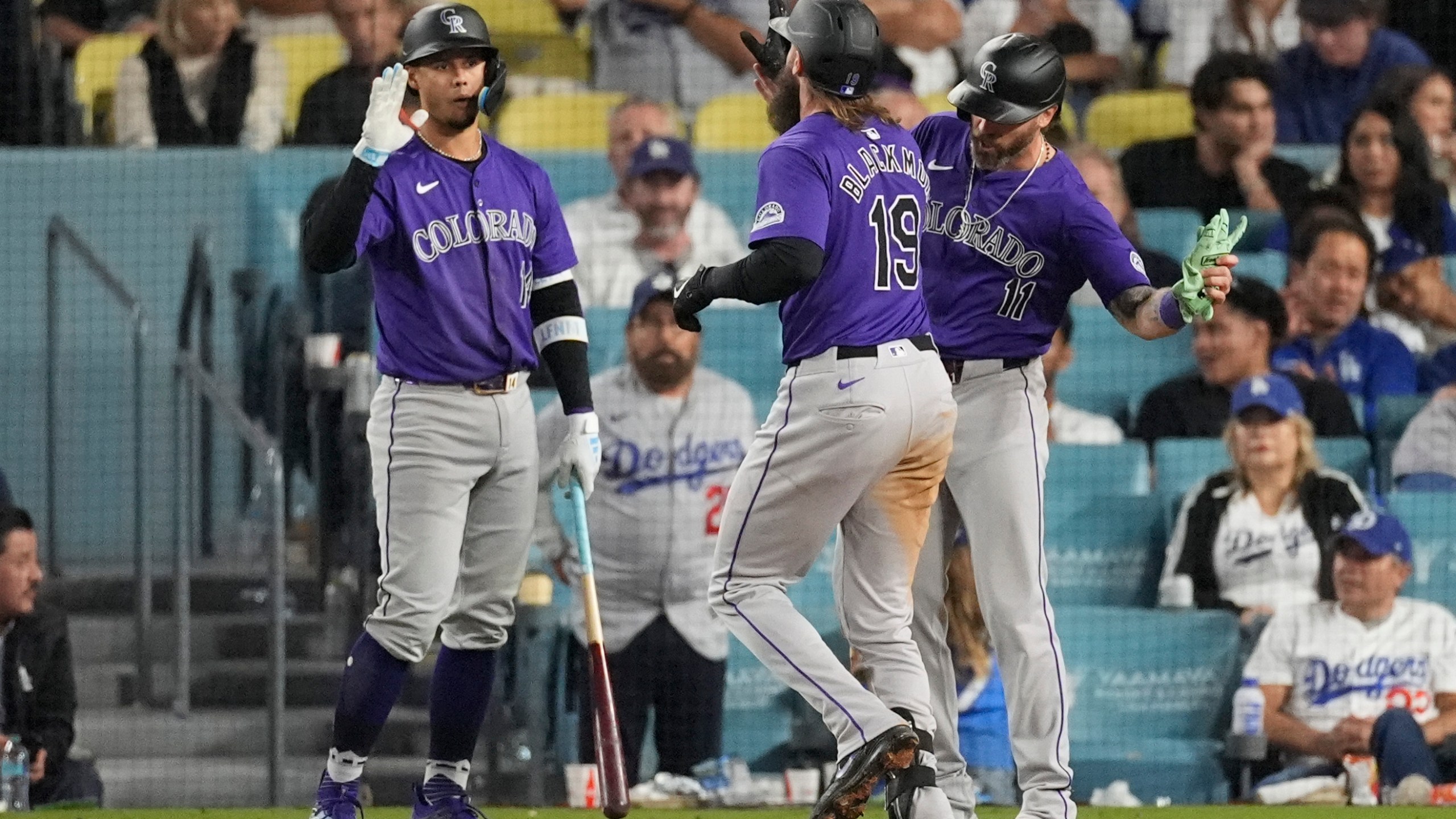 Colorado Rockies designated hitter Charlie Blackmon (19) celebrates with Jake Cave (11) and Ezequiel Tovar (14) after hitting a home run during the ninth inning of a baseball game against the Los Angeles Dodgers in Los Angeles, Saturday, Sept. 21, 2024. Cave also scored. (AP Photo/Ashley Landis)