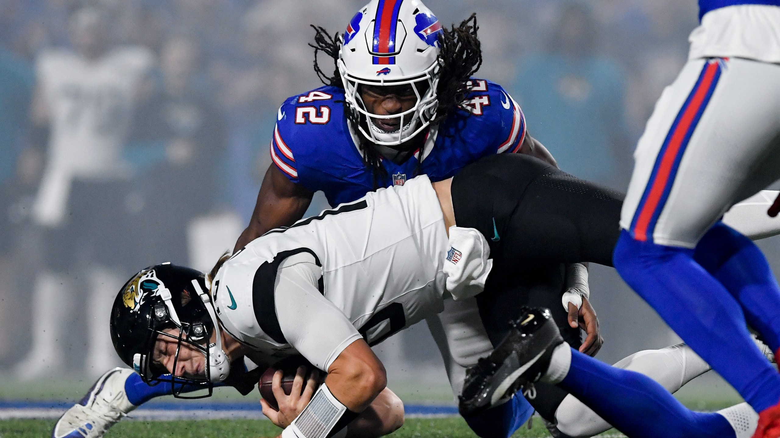 Jacksonville Jaguars quarterback Trevor Lawrence (16) lunges for yardage under Buffalo Bills linebacker Dorian Williams (42) during the first half of an NFL football game against the Buffalo Bills, Monday, Sept. 23, 2024, in Orchard Park, NY. (AP Photo/Adrian Kraus)