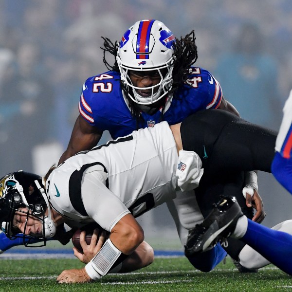 Jacksonville Jaguars quarterback Trevor Lawrence (16) lunges for yardage under Buffalo Bills linebacker Dorian Williams (42) during the first half of an NFL football game against the Buffalo Bills, Monday, Sept. 23, 2024, in Orchard Park, NY. (AP Photo/Adrian Kraus)