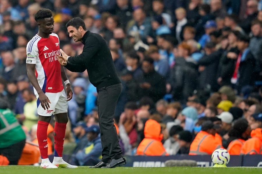 Arsenal's manager Mikel Arteta speaks to Arsenal's Bukayo Saka during the English Premier League soccer match between Manchester City and Arsenal at the Etihad stadium in Manchester, England, Sunday, Sept. 22, 2024. (AP Photo/Dave Thompson)