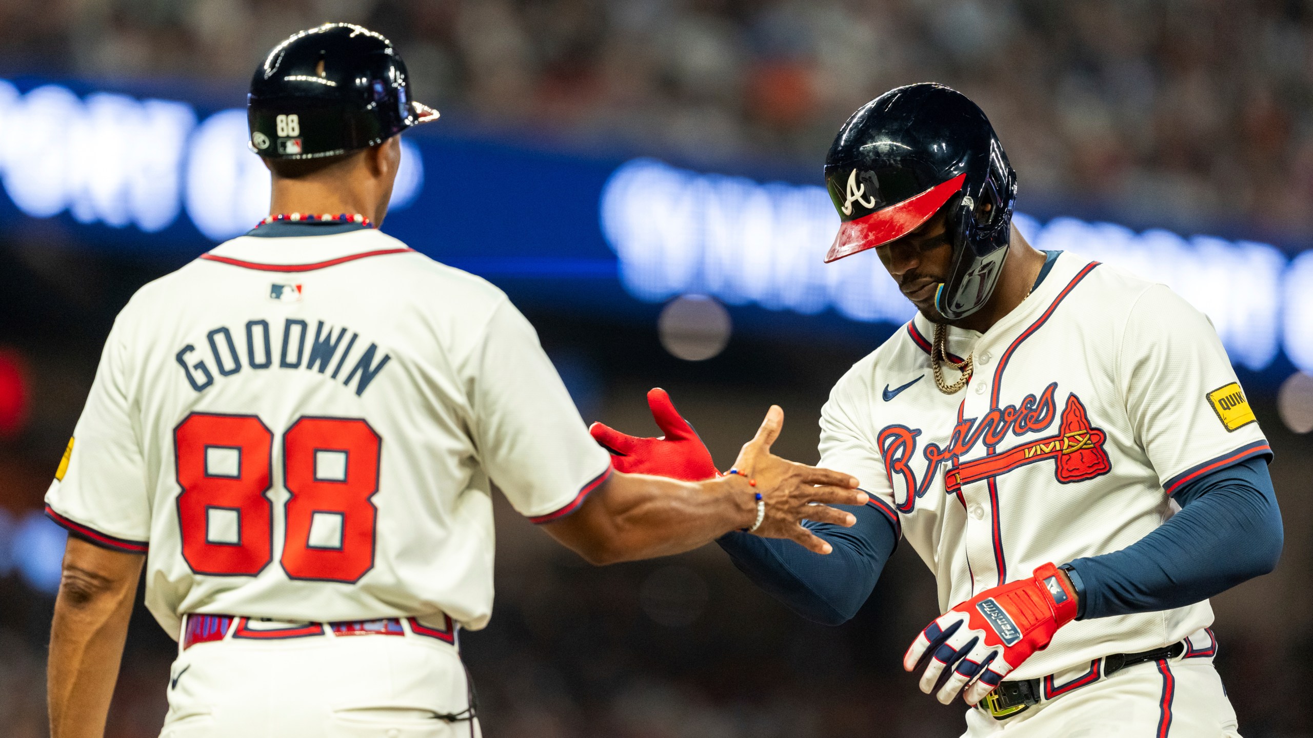 Atlanta Braves' Jorge Soler, right, high fives first base coach Tom Goodwin, left, after hitting a single in the fifth inning of a baseball game against the New York Mets, Tuesday, Sept. 24, 2024, in Atlanta. (AP Photo/Jason Allen)