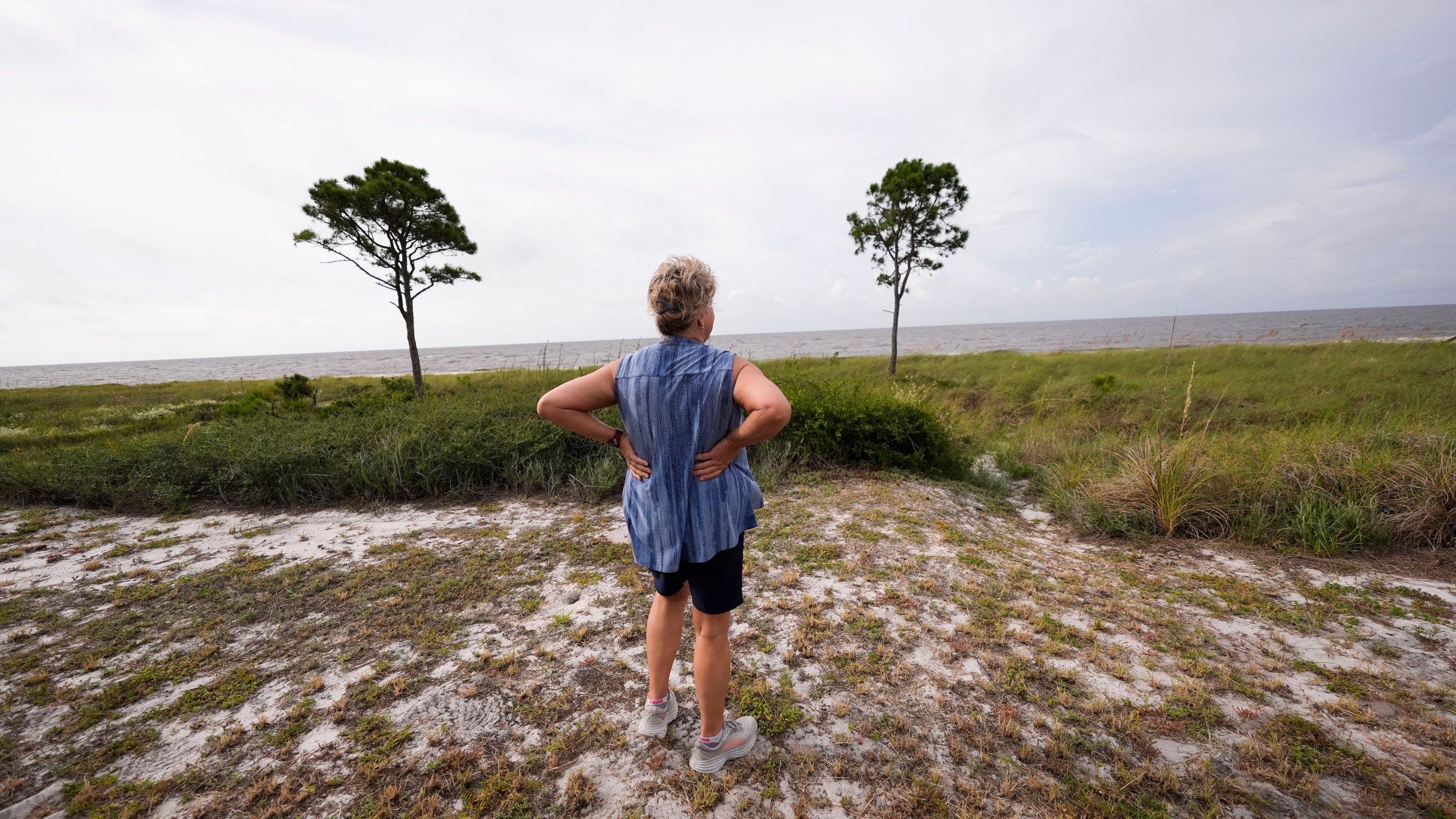 Paulette McLin takes in the scene outside their summer home ahead of Hurricane Helene, expected to make landfall Thursday evening, in Alligator Point, Fla., Wednesday, Sept. 25, 2024. (AP Photo/Gerald Herbert)