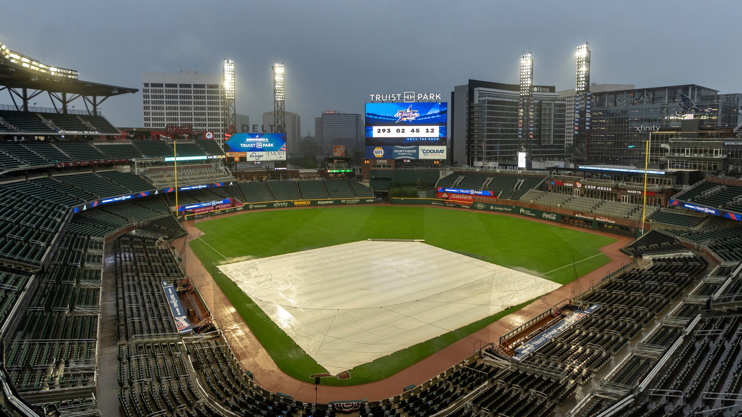 A tarp covers the infield as rain comes down at Truist Park after the baseball game between the New York Mets and Atlanta Braves as postponed, Wednesday, Sept. 25, 2024, in Atlanta. The Mets-Braves games scheduled for Wednesday and Thursday are postponed and will be made up as a doubleheader Monday, Sept. 30. (AP Photo/Jason Allen)