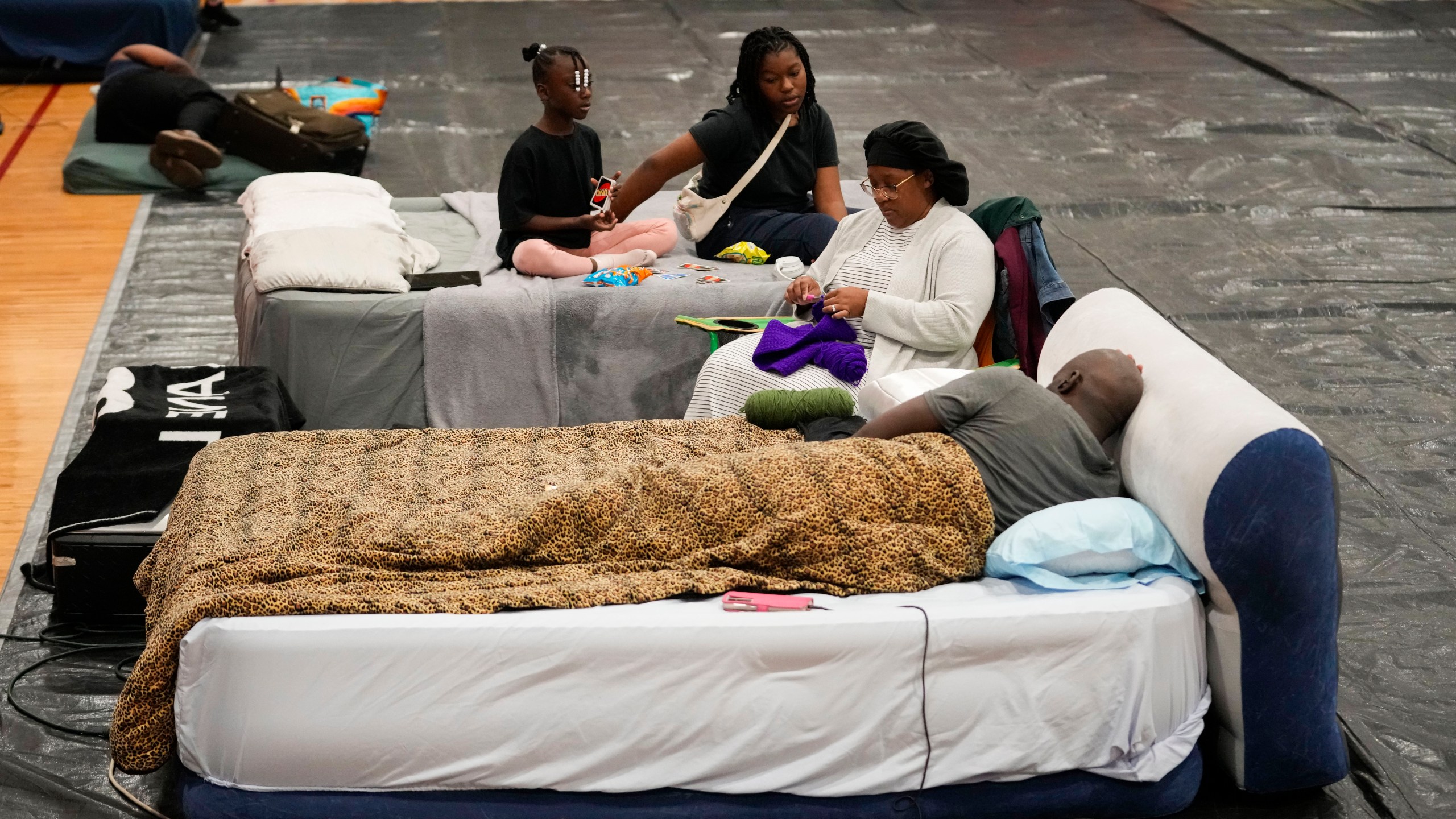 Sharonda and Victor Davis, of Tallahassee, sit with their children Victoria background left, and Amaya, background right, inside a hurricane evacuation shelter at Fairview Middle School, ahead of Hurricane Helene, expected to make landfall here today, in Leon County, Fla., Thursday, Sept. 26, 2024. (AP Photo/Gerald Herbert)