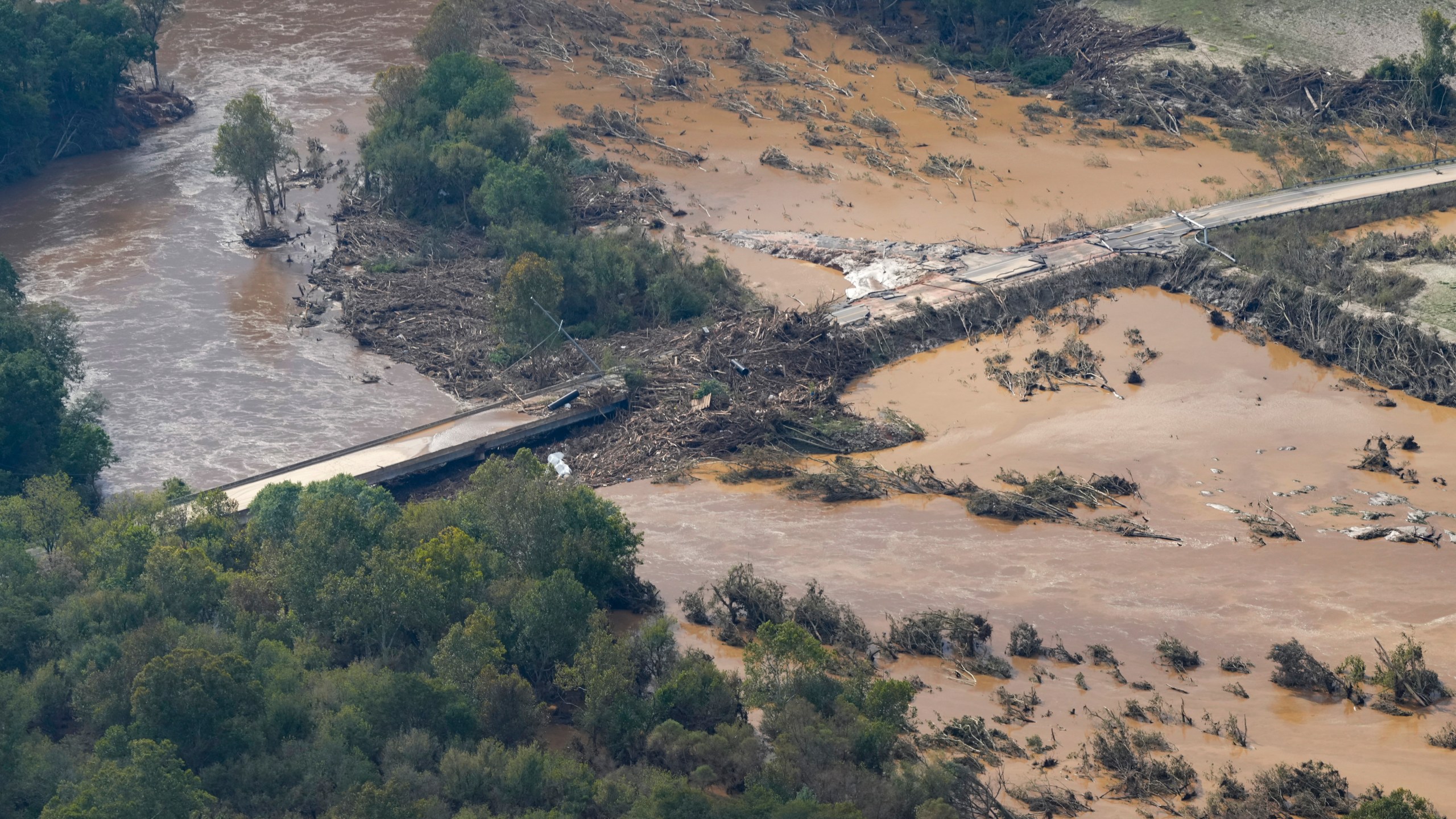 An aerial view a damaged bridge and flooding in the aftermath of Hurricane Helene is seen along the Nolichucky River, Saturday, Sept. 28, 2024, in Greene County, Tenn. (AP Photo/George Walker IV)