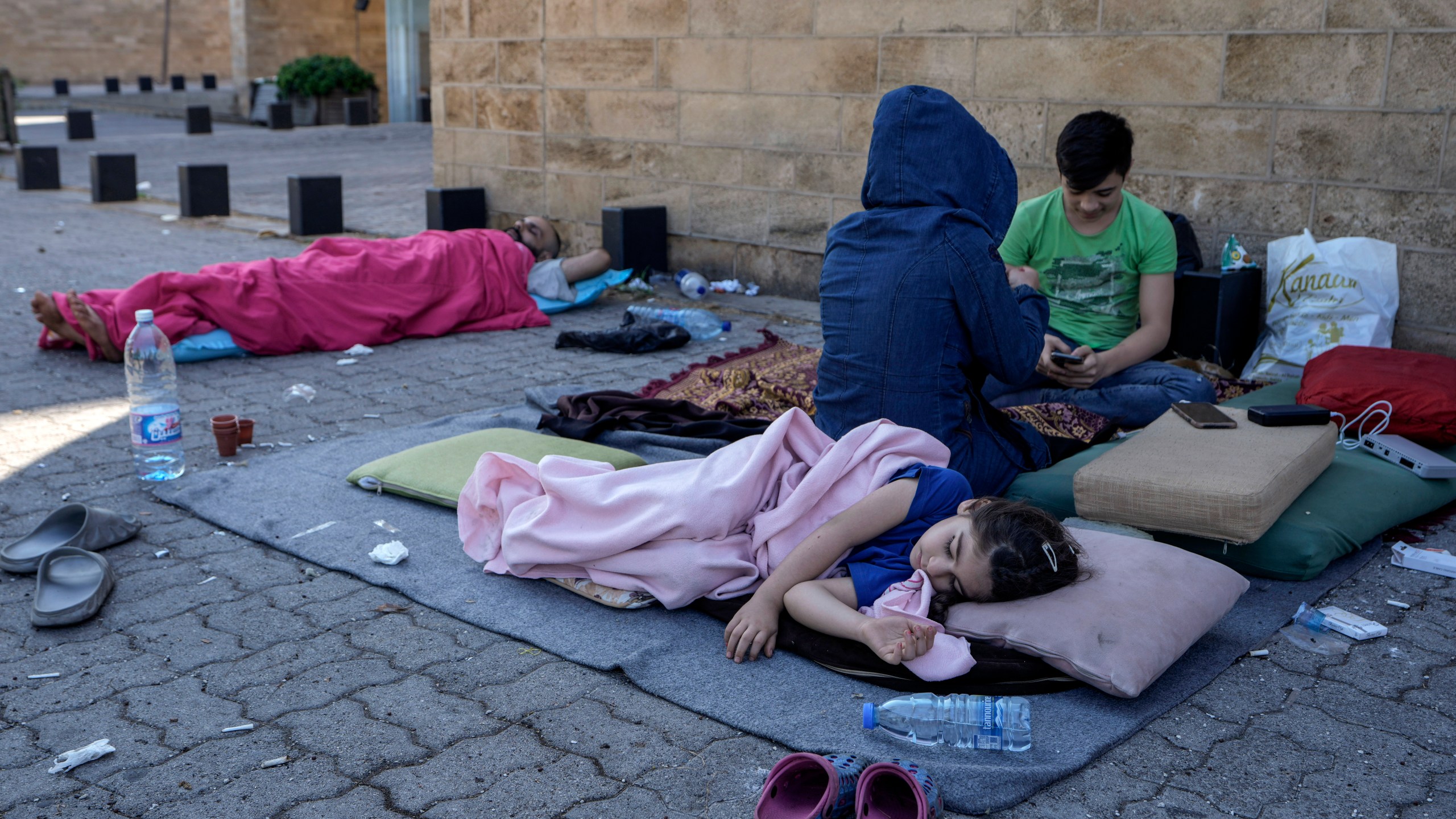 A family sleep on the ground in Beirut's corniche area after fleeing the Israeli airstrikes in the southern suburbs of Dahiyeh, Sunday, Sept. 29, 2024. (AP Photo/Bilal Hussein)