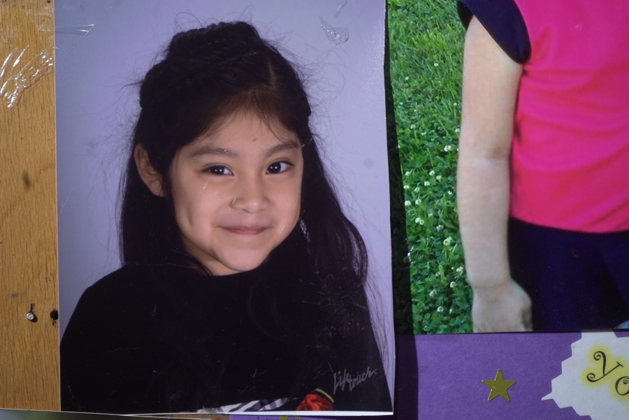 A photo of a smiling girl with dark hair and eyes.