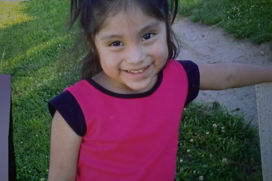 A smiling girl in a pink tank top.