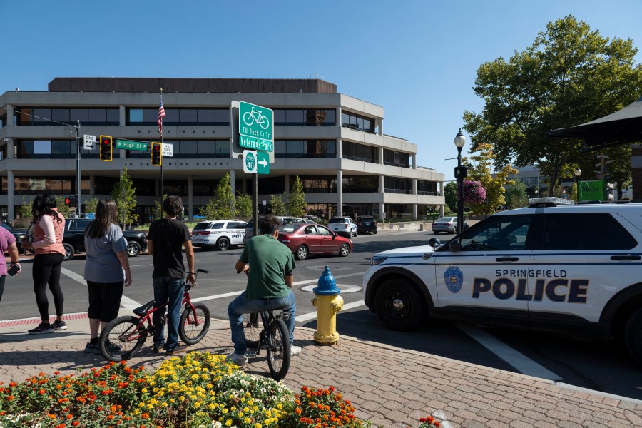 People watch as Springfield Police Department officers investigate the Springfield City Hall after bomb threats were made.