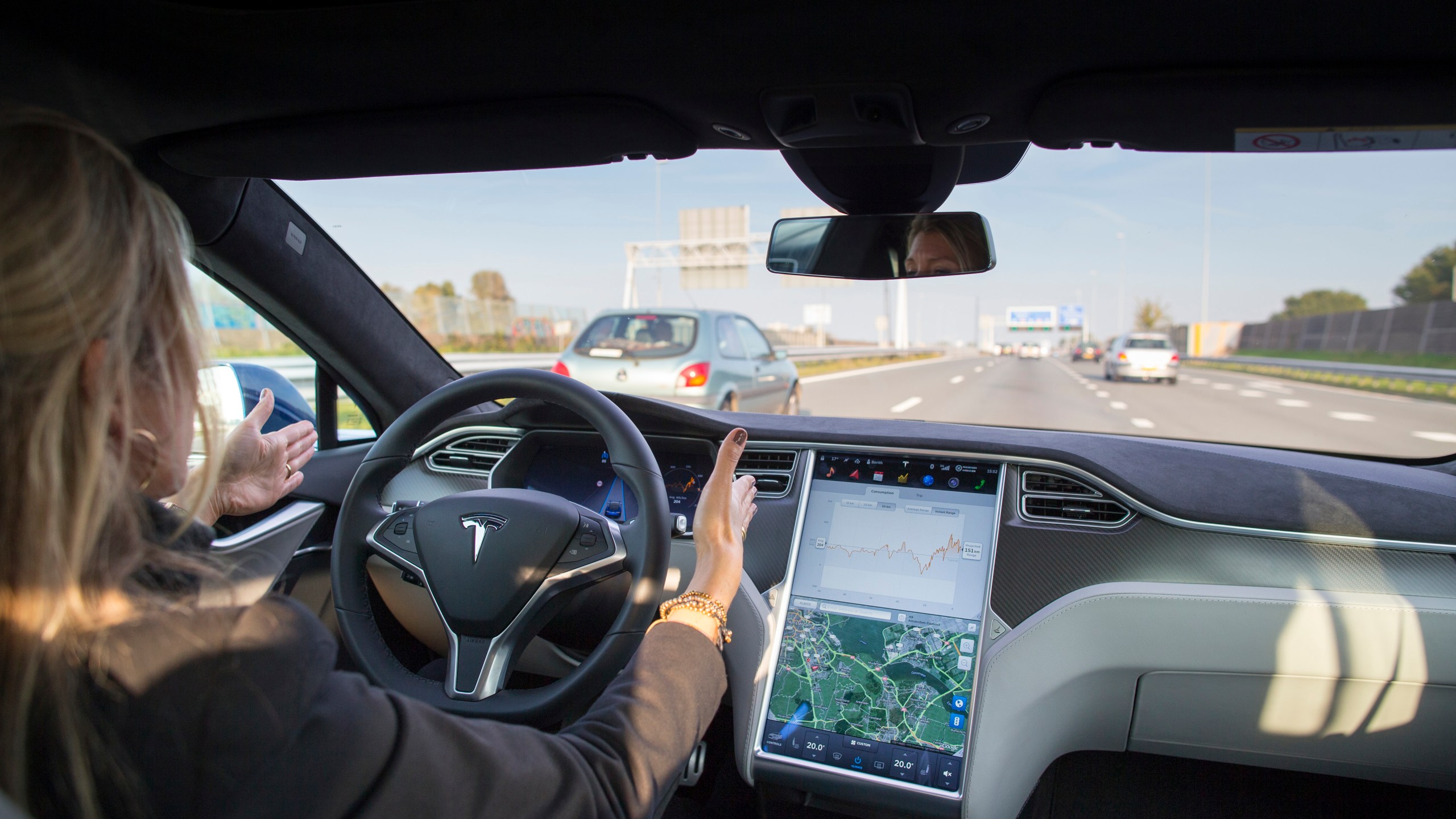 An employee drives a Tesla Model S electric automobile, equipped with Autopilot hardware and software, hands-free on a highway