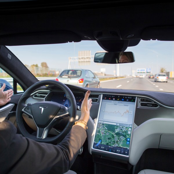 An employee drives a Tesla Model S electric automobile, equipped with Autopilot hardware and software, hands-free on a highway