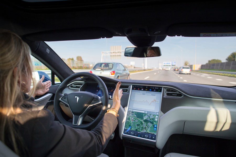 An employee drives a Tesla Model S electric automobile, equipped with Autopilot hardware and software, hands-free on a highway