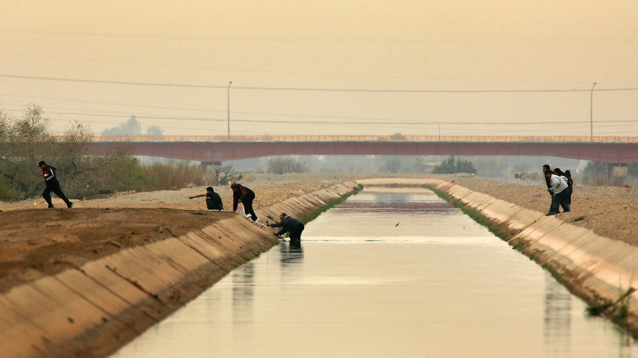 People cross a canal after walking over the dry Colorado River to cross illegally into the U.S. from Mexico on March 16, 2006 the border town of near San Luis, south of Yuma, Arizona.