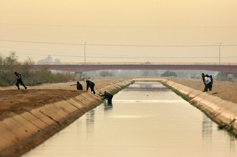 People cross a canal after walking over the dry Colorado River to cross illegally into the U.S. from Mexico on March 16, 2006 the border town of near San Luis, south of Yuma, Arizona.