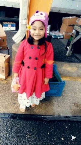 A young girl in a white hat and pink coat.