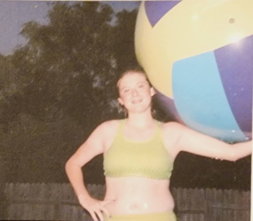 A teen girl in a halter top with a beach ball.