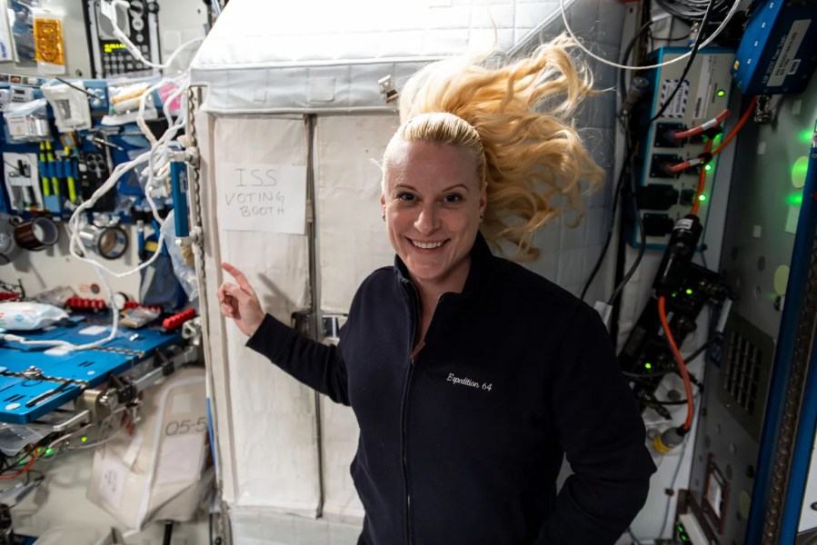 NASA astronaut Kate Rubins in 2020, pointing  to the International Space Station’s “voting booth” where she cast her vote from space. 