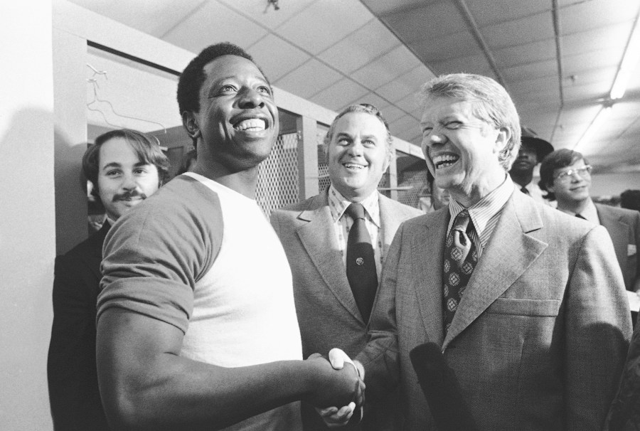 FILE - Georgia Gov. Jimmy Carter, right, and Delaware Gov. Sherman Tribbitt say hello to Atlanta Braves Hank Aaron, left, following a rain canceled game with the Los Angeles Dodgers in Atlanta, Ga., Sept. 27, 1973. (AP Photo, File)