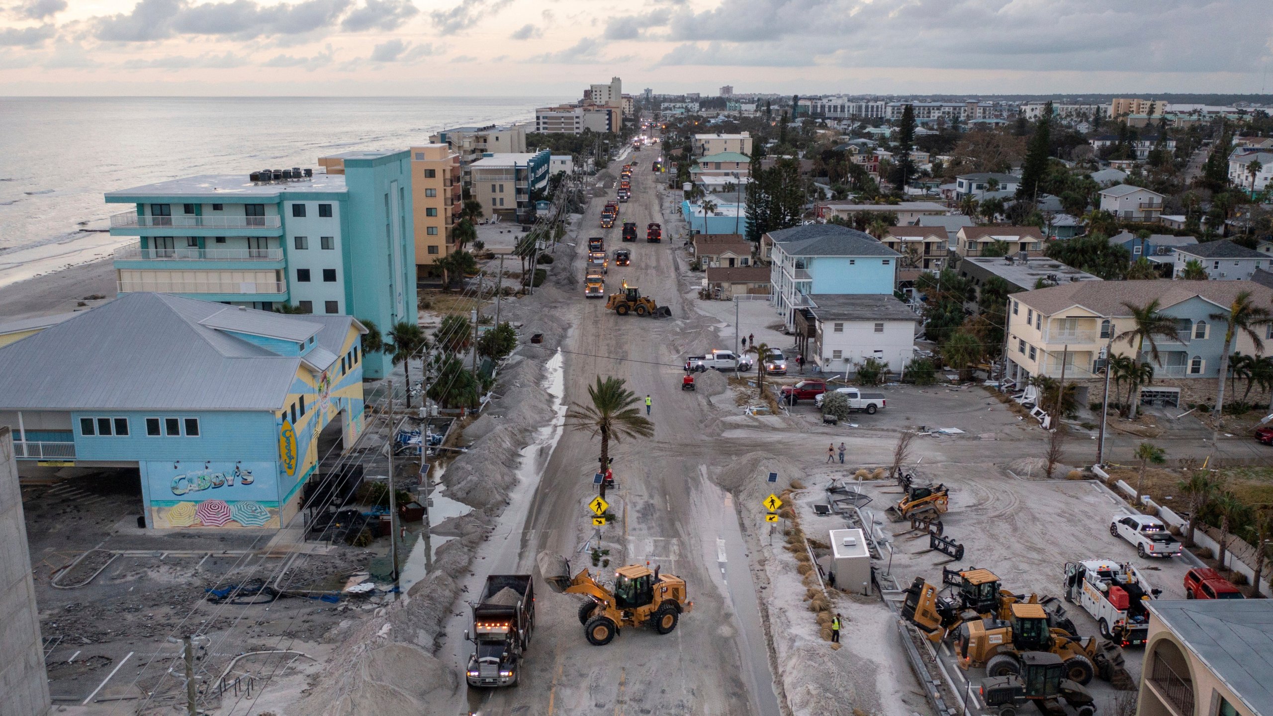 Crews work to clean up the tons of sand and debris pushed onto Gulf Boulevard from Hurricane Helene storm surge, Saturday, Sept. 28, 2024, in Madeira Beach, Fla. (Luis Santana/Tampa Bay Times via AP)