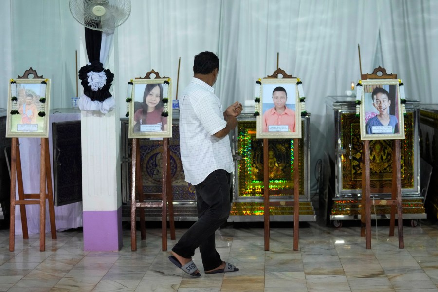 A relative of the bus fire victims walks in front of their coffins at the Wat Khao Phraya Sangkharam School Lan Sak , Uthai Thani province, Thailand, Wednesday, Oct. 2, 2024. (AP Photo/Sakchai Lalit)