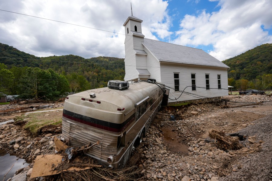 A bus pushed by flood waters rests against Laurel Branch Baptist church in the aftermath of Hurricane Helene, Thursday, Oct. 3, 2024, in Pensacola, N.C. (AP Photo/Mike Stewart)