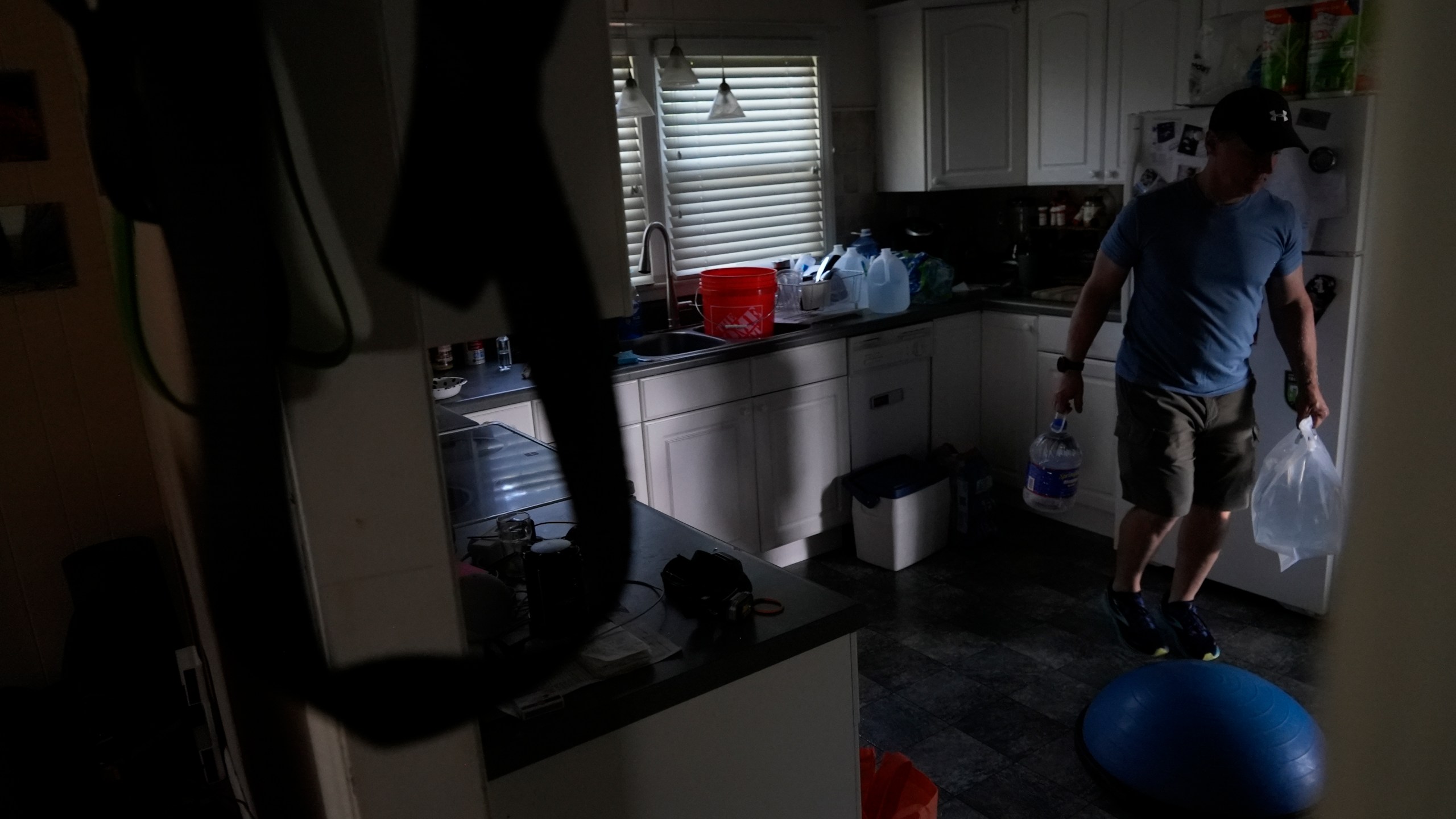 Travis Edwards organizes his drinking water supply Thursday, Oct. 3, 2024 in Asheville, North Carolina. He hasn't had water since Hurricane Helene struck the area, and reuses water to flush toilets. (AP Photo/Brittany Peterson)