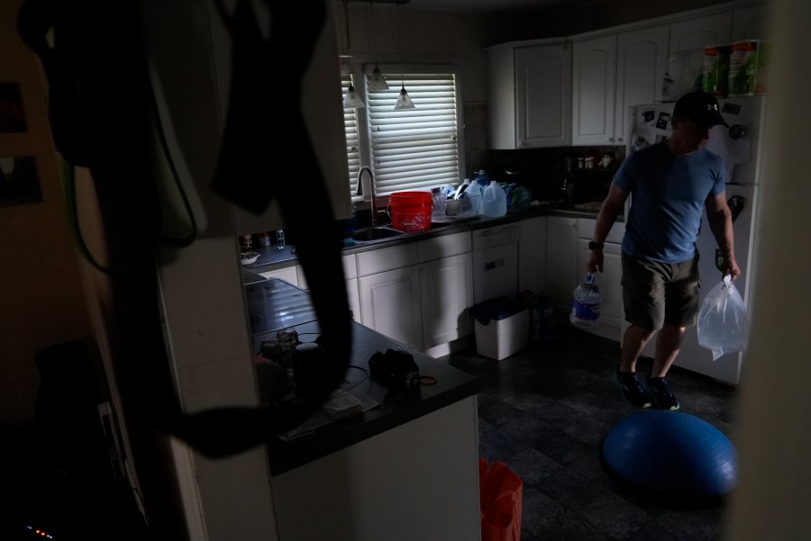 Travis Edwards organizes his drinking water supply Thursday, Oct. 3, 2024 in Asheville, North Carolina. He hasn't had water since Hurricane Helene struck the area, and reuses water to flush toilets. (AP Photo/Brittany Peterson)