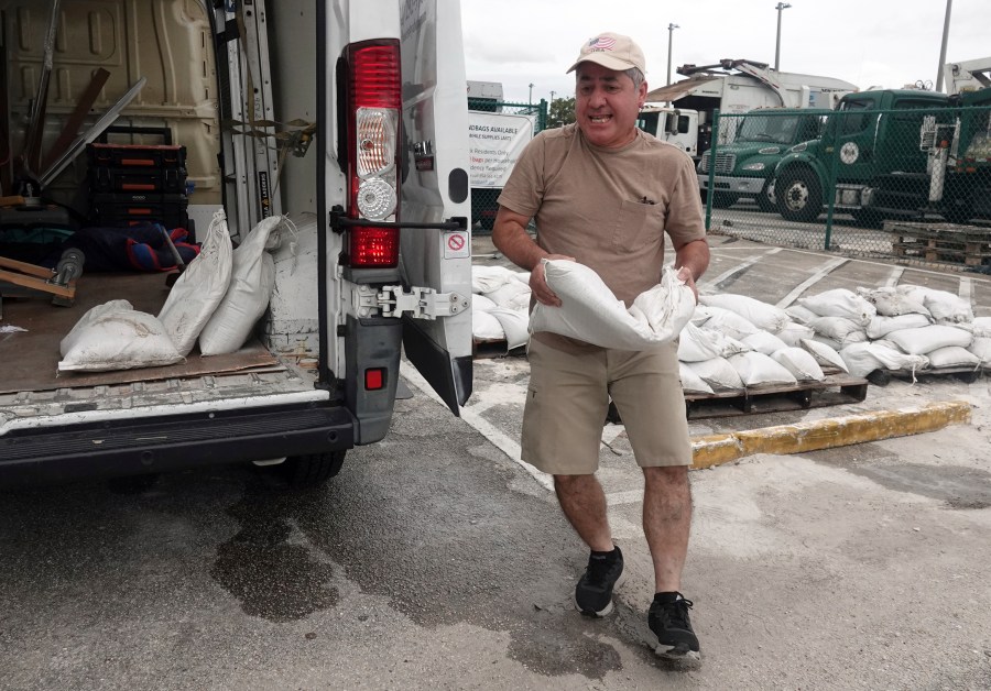 Nelson Hoyos loads sandbags for his business in Oakland Park, Fla., Sunday, Oct. 6, 2024, as Florida is in for a wet week as the storm nears the west coast. (Joe Cavaretta/South Florida Sun-Sentinel via AP)