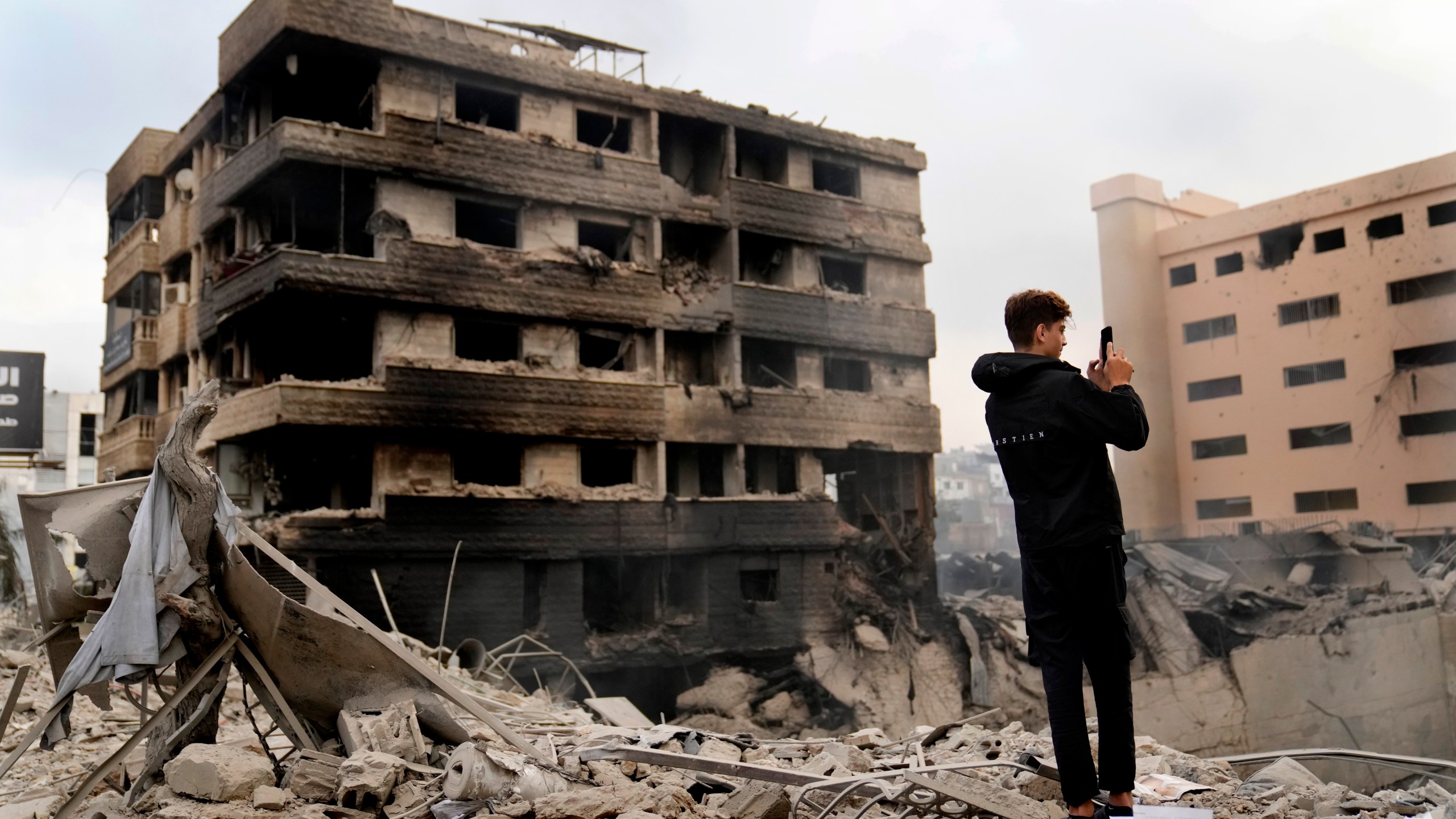 A man takes pictures by his mobile phone of destroyed buildings hit by Israeli airstrikes in Dahiyeh, Beirut, Lebanon, Monday, Oct. 7, 2024. (AP Photo/Hussein Malla)