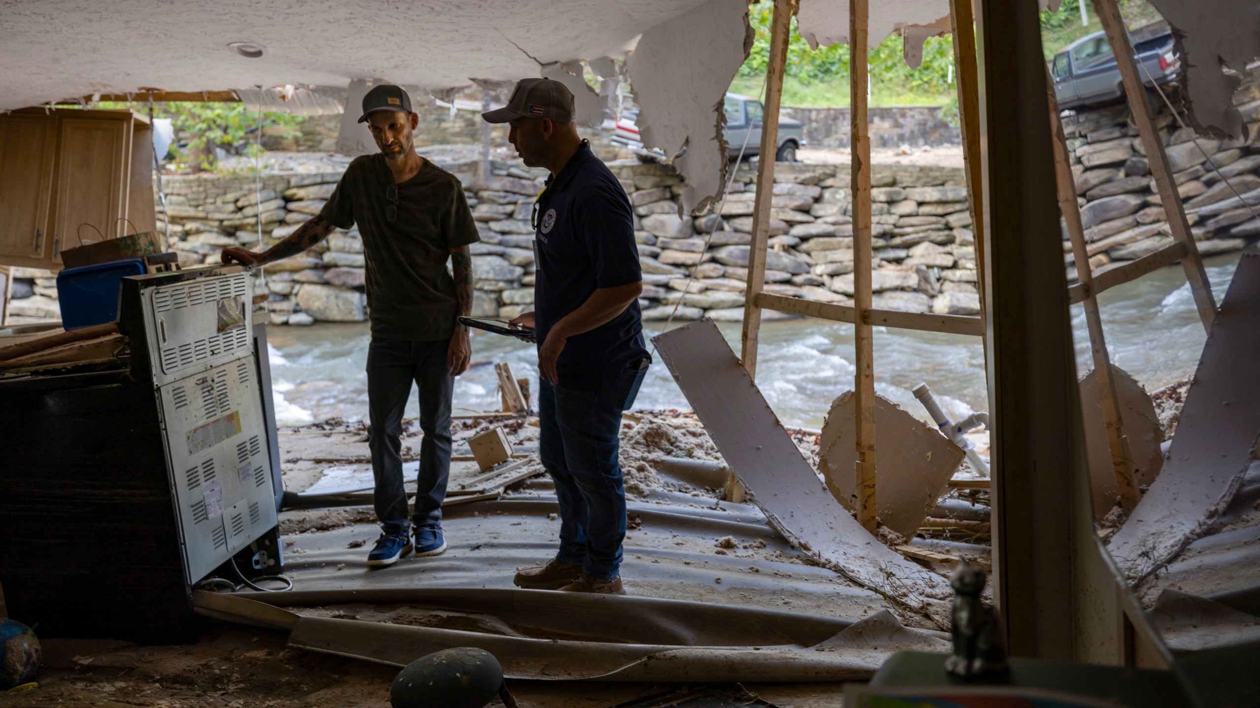 FEMA employee Jirau Alvaro works with Daniel Mancini, doing a report on the damage to his property on Sunday, Oct. 6, 2024 in rural Buncombe County, near Black Mountain, N.C. (Robert Willett/The News & Observer via AP)