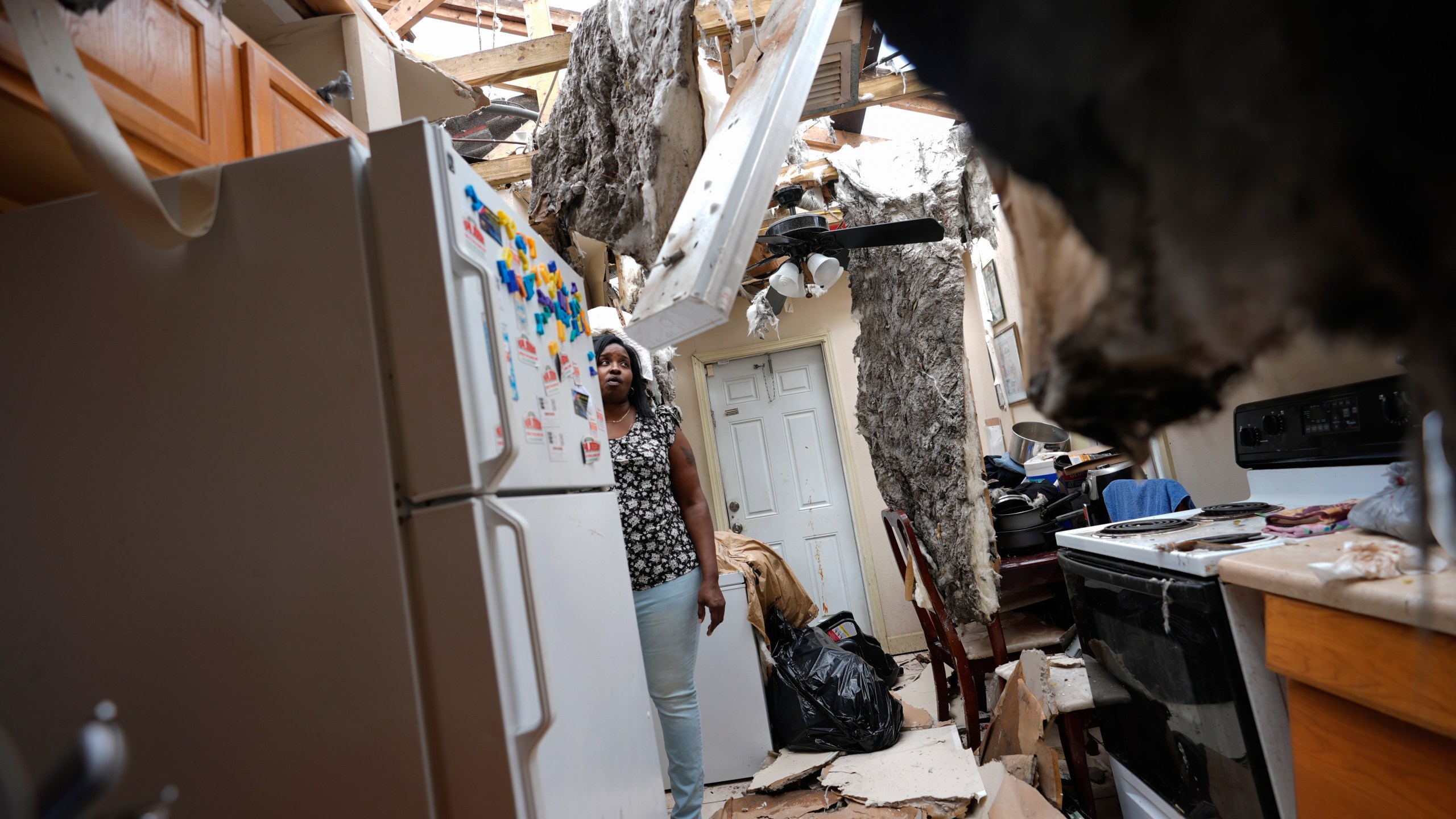 Natasha Ducre surveys the kitchen of her devastated home, which lost most of its roof during the passage of Hurricane Milton, in Palmetto, Fla., Thursday, Oct. 10, 2024. Ducre, her husband, three children and two grandkids, rode out the storm in a government shelter and returned to find their home unlivable and much of their furniture and belongings destroyed by rainwater. (AP Photo/Rebecca Blackwell)