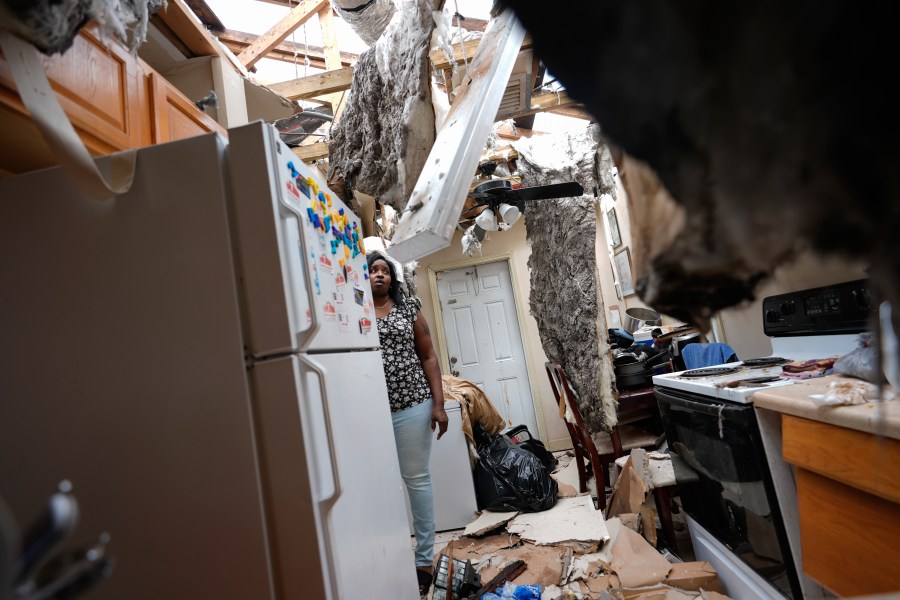 Natasha Ducre surveys the kitchen of her devastated home, which lost most of its roof during the passage of Hurricane Milton, in Palmetto, Fla., Thursday, Oct. 10, 2024. Ducre, her husband, three children and two grandkids, rode out the storm in a government shelter and returned to find their home unlivable and much of their furniture and belongings destroyed by rainwater. (AP Photo/Rebecca Blackwell)