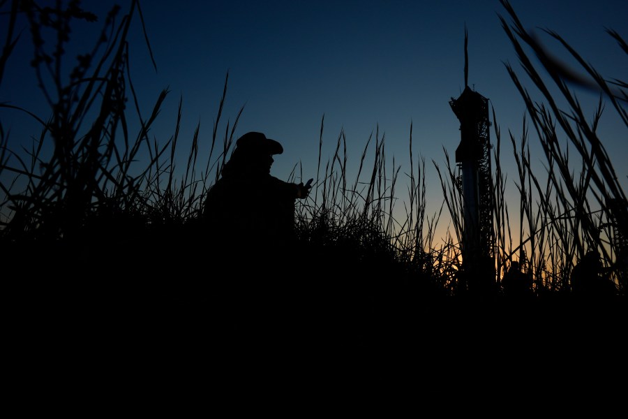 Noah Jansko watches as the sun sets behind SpaceX's mega rocket Starship, Saturday, Oct. 12, 2024, in Boca Chica, Texas. (AP Photo/Eric Gay)