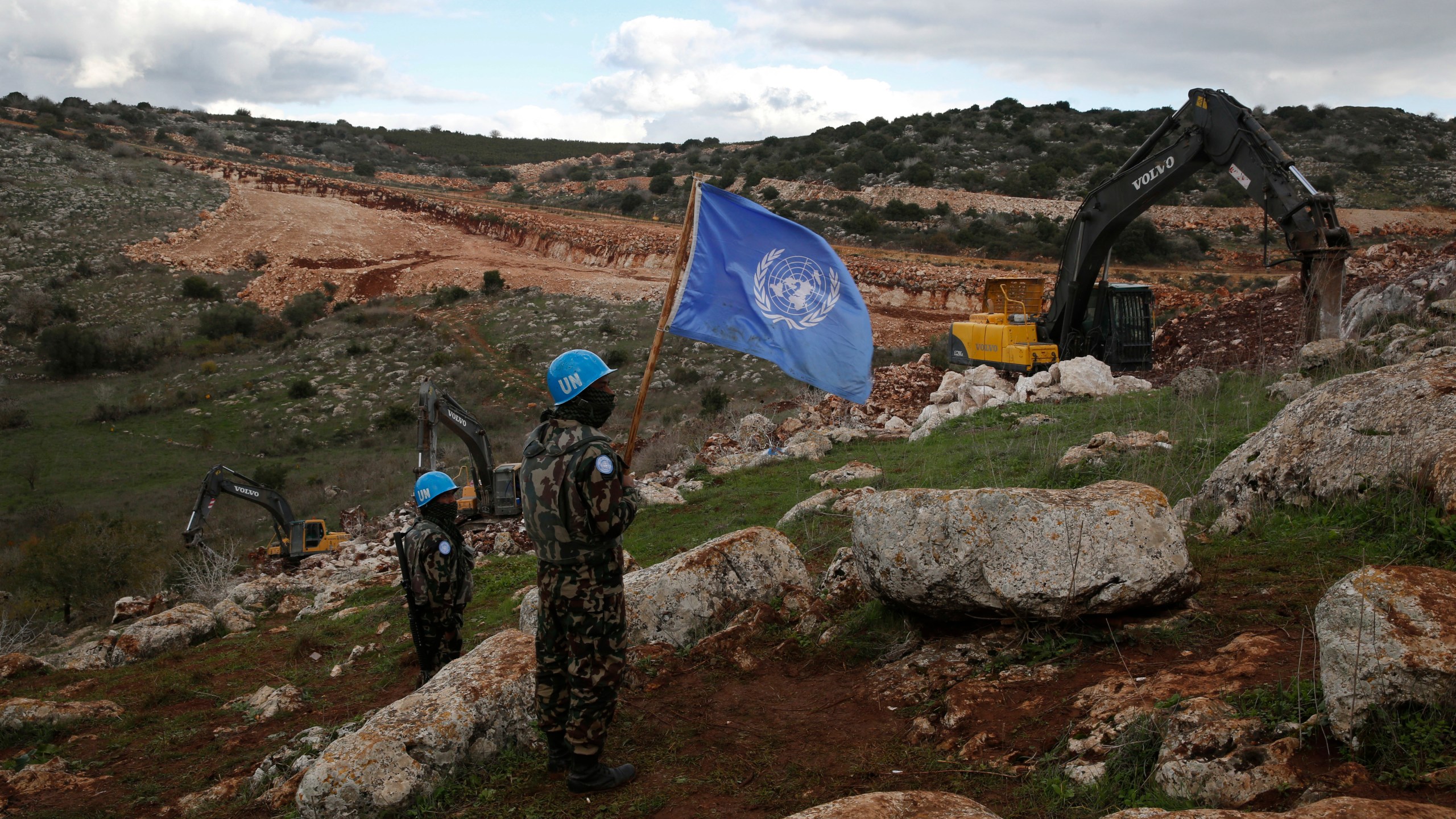 FILE - UN peacekeepers hold their flag, as they observe Israeli excavators attempt to destroy tunnels built by Hezbollah, near the southern Lebanese-Israeli border village of Mays al-Jabal, Lebanon, Dec. 13, 2019. (AP Photo/Hussein Malla, File)