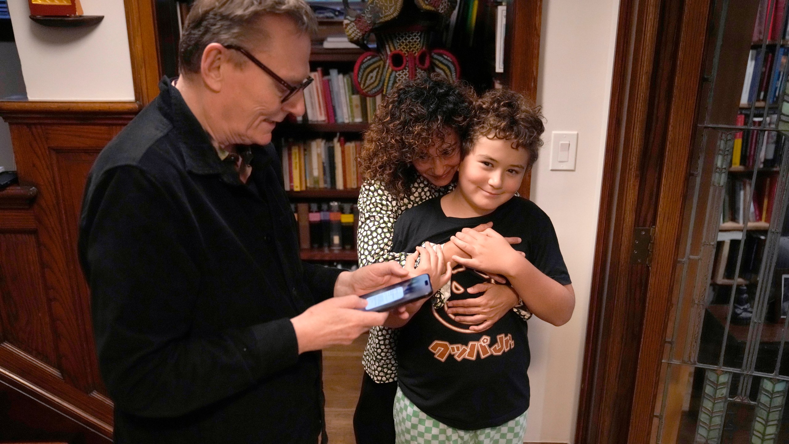 Nobel prize winner in Economics, James A. Robinson, looks over a selfie he made for the Nobel Foundation with his wife Dr. Maria Angelica Bautista, and son Adrian at their home in the Hyde Park neighborhood of Chicago, Monday, Oct. 14, 2024. (AP Photo/Charles Rex Arbogast)