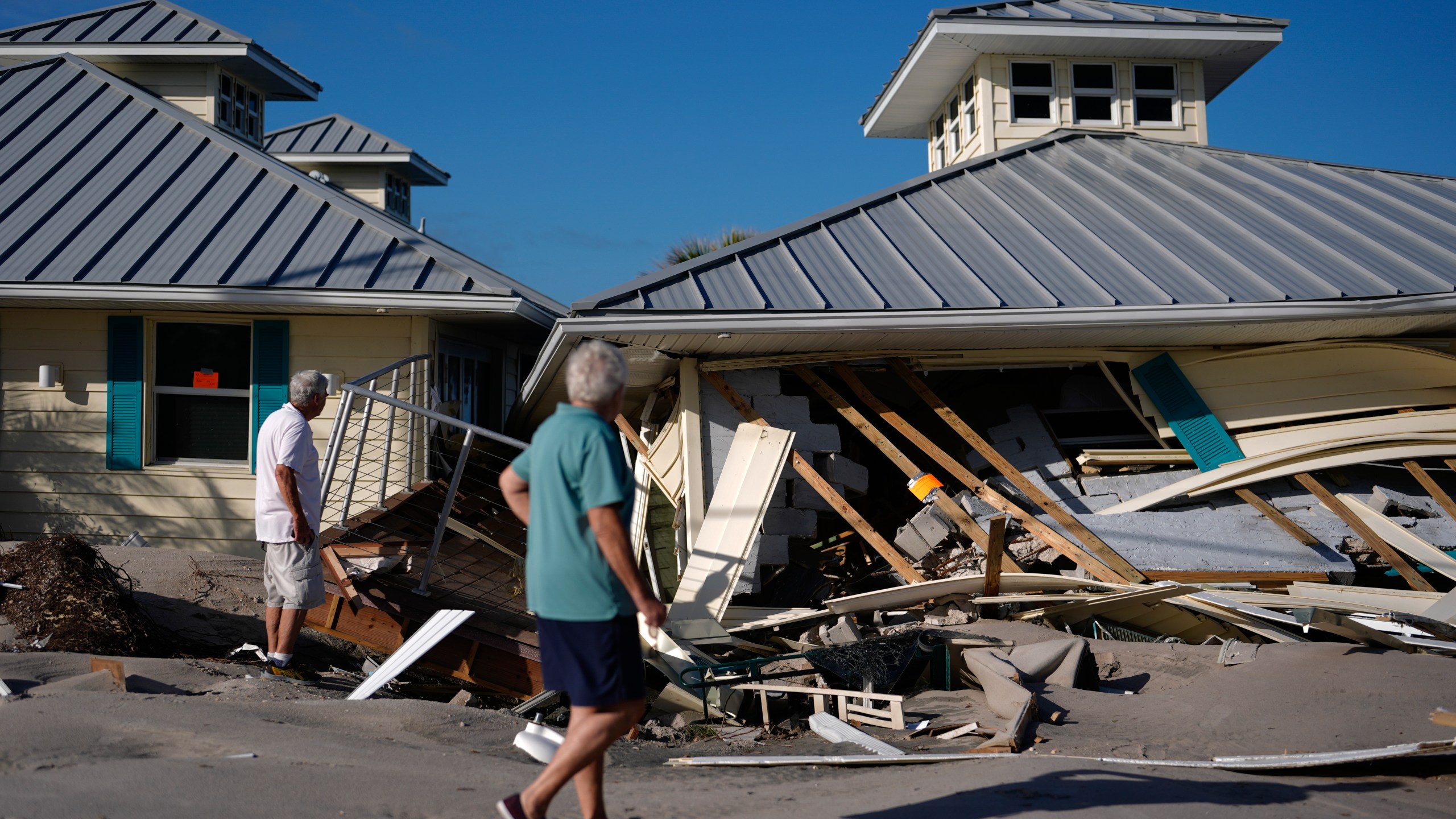 Property owners who preferred not to be named assess damage to their home and business, which bears orange notices calling for demolition, after the passage of Hurricane Milton, on Manasota Key in Englewood, Fla., Sunday, Oct. 13, 2024. (AP Photo/Rebecca Blackwell)