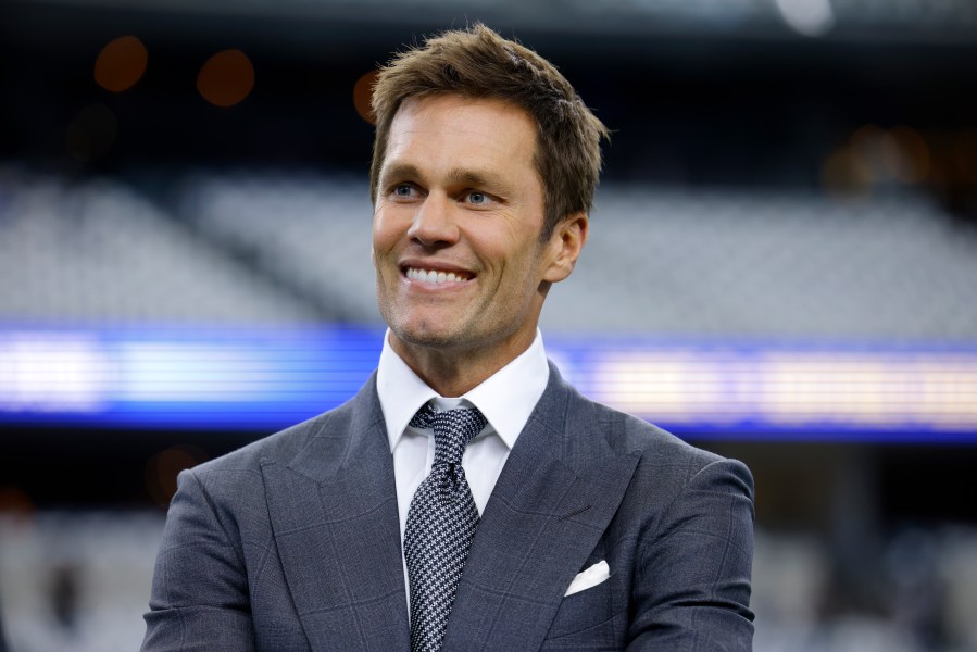 Fox Sports lead NFL analyst Tom Brady stands on the field during warmups before an NFL football game between the Detroit Lions and the Dallas Cowboys in Arlington, Texas, Sunday, Oct. 13, 2024. (AP Photo/Gareth Patterson)