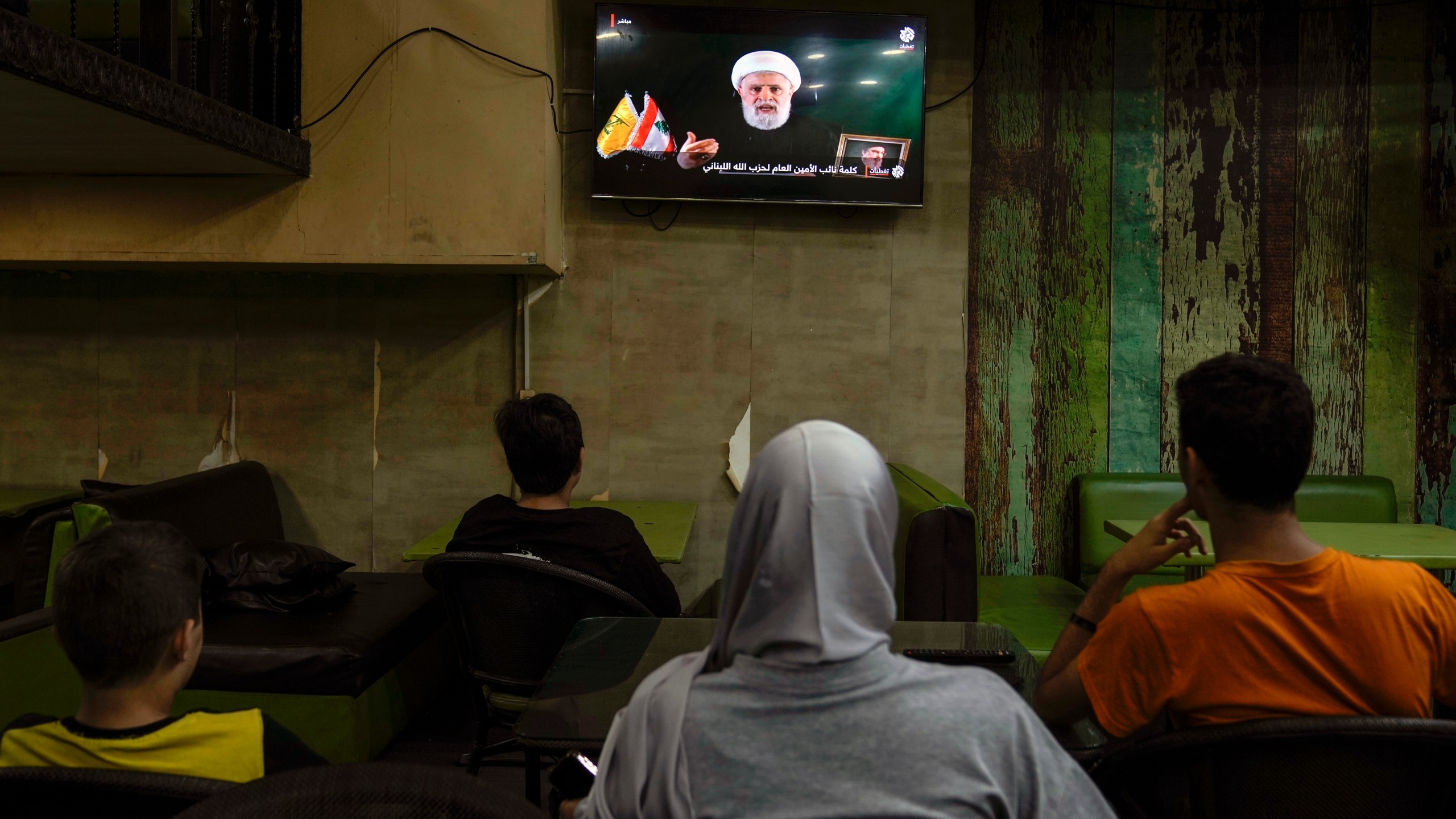 People listen to a speech by Naim Kassem, acting leader of Hezbollah, broadcasted on a television channel, at a coffee shop in Beirut, Lebanon, Tuesday, Oct. 15, 2024. (AP Photo/Bilal Hussein)