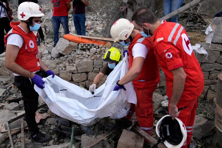 Lebanese Red Cross volunteers remove the remains of killed people from the rubble of a destroyed building at the site of Monday's Israeli airstrike in Aito village, north Lebanon, Tuesday, Oct. 15, 2024. (AP Photo/Hussein Malla)